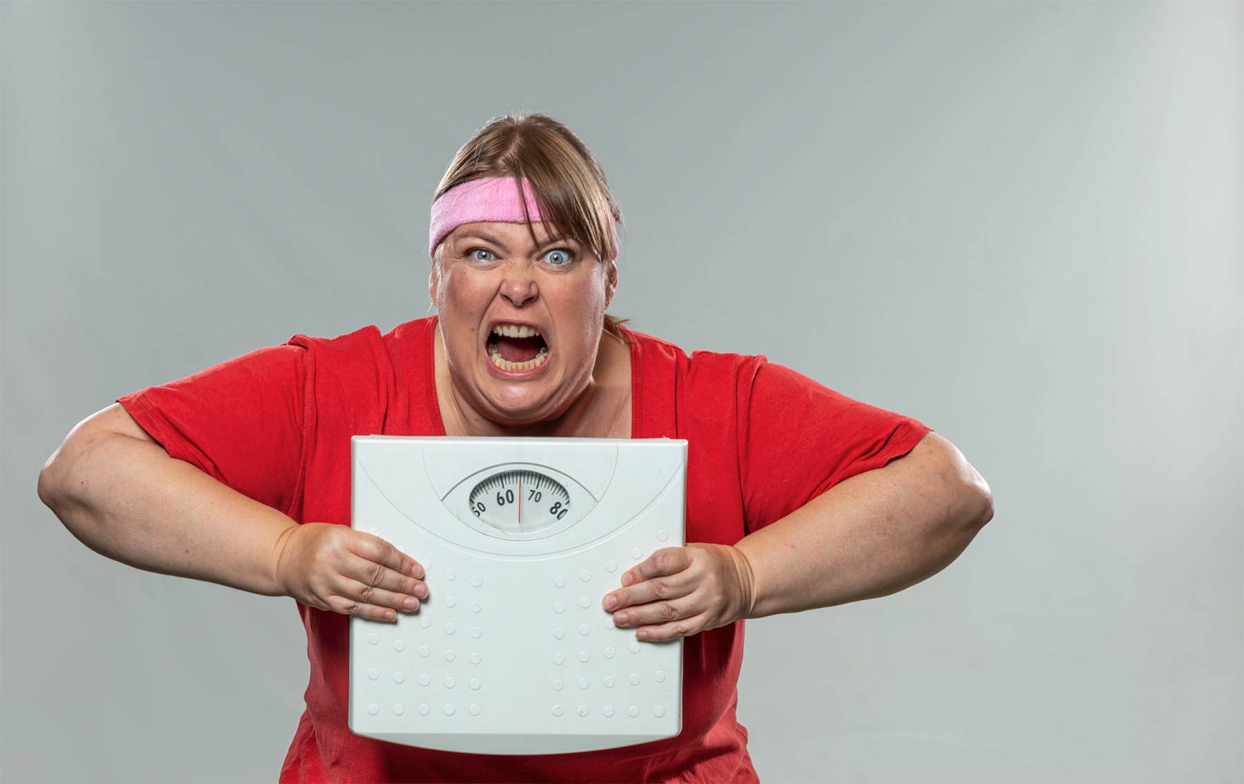 Screenshot Image of a person looking slightly frustrated or overwhelmed while holding a scale